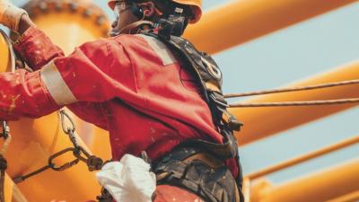 A construction worker wearing personal protective equipment and a harness working on a structure.